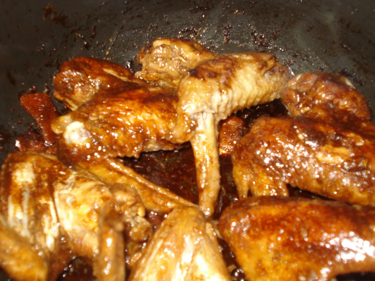 Cooked chicken adobo pieces coated in a glossy brown soy-and-vinegar sauce in a pan